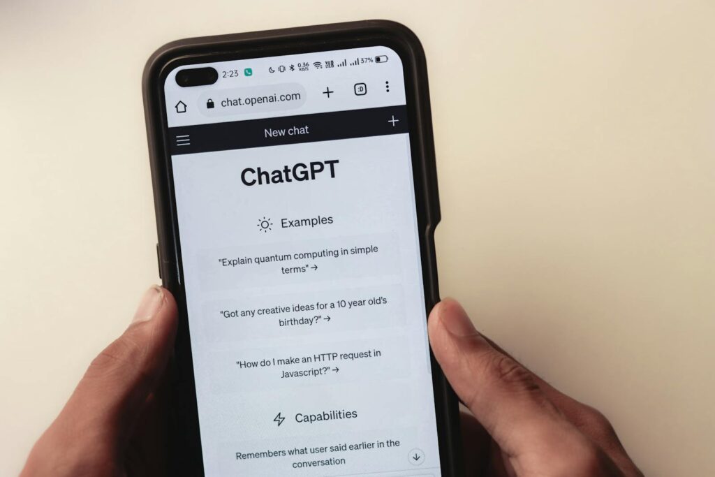 Hands holding a smartphone displaying the ChatGPT interface on its screen with example questions and capabilities listed, now powered by GPT-4o.