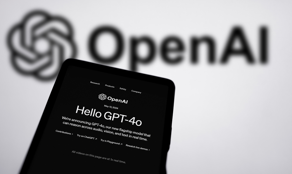 A digital tablet displaying the OpenAI website with an announcement for "Hello GPT-4o," against a blurred background featuring the OpenAI logo.