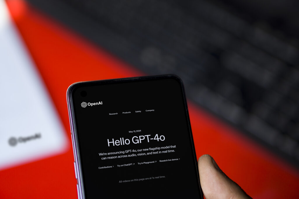 Close-up view of a smartphone held in hand displaying the OpenAI website with the announcement for "Hello GPT-4o."