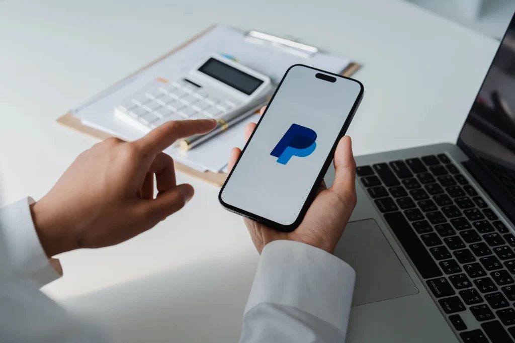 Person using a smartphone with the PayPal app open, representing the PayPal ChatGPT Integration and upcoming in-chat payment features.