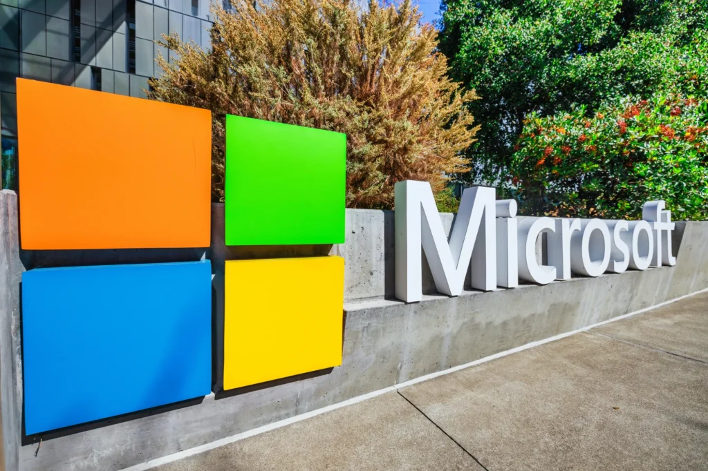 Microsoft office building exterior with company logo displayed on glass facade, representing Copilot Tasks and Microsoft AI initiatives.