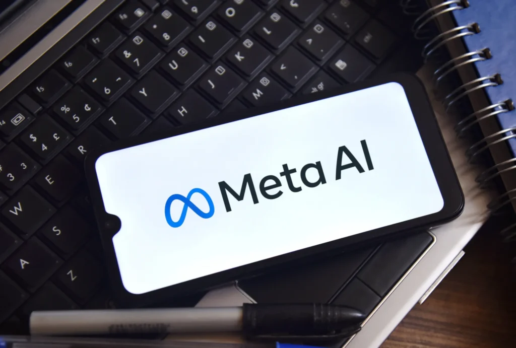 AI Shopping Tool image showing the Meta AI logo on a smartphone resting on a keyboard beside a pen and notebook, representing the Meta AI platform behind the shopping feature.